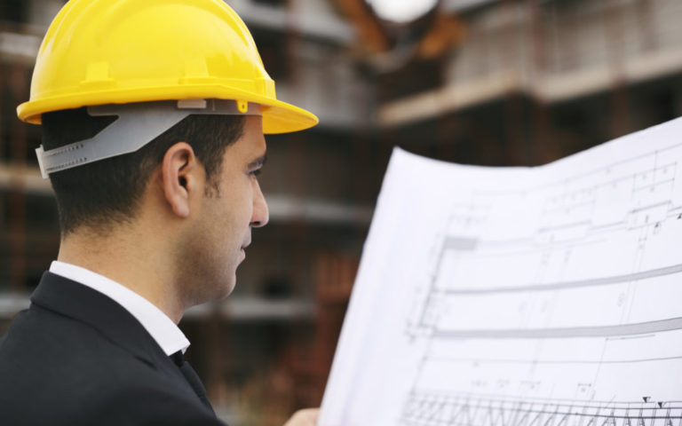 Architect in construction site looking at building plans